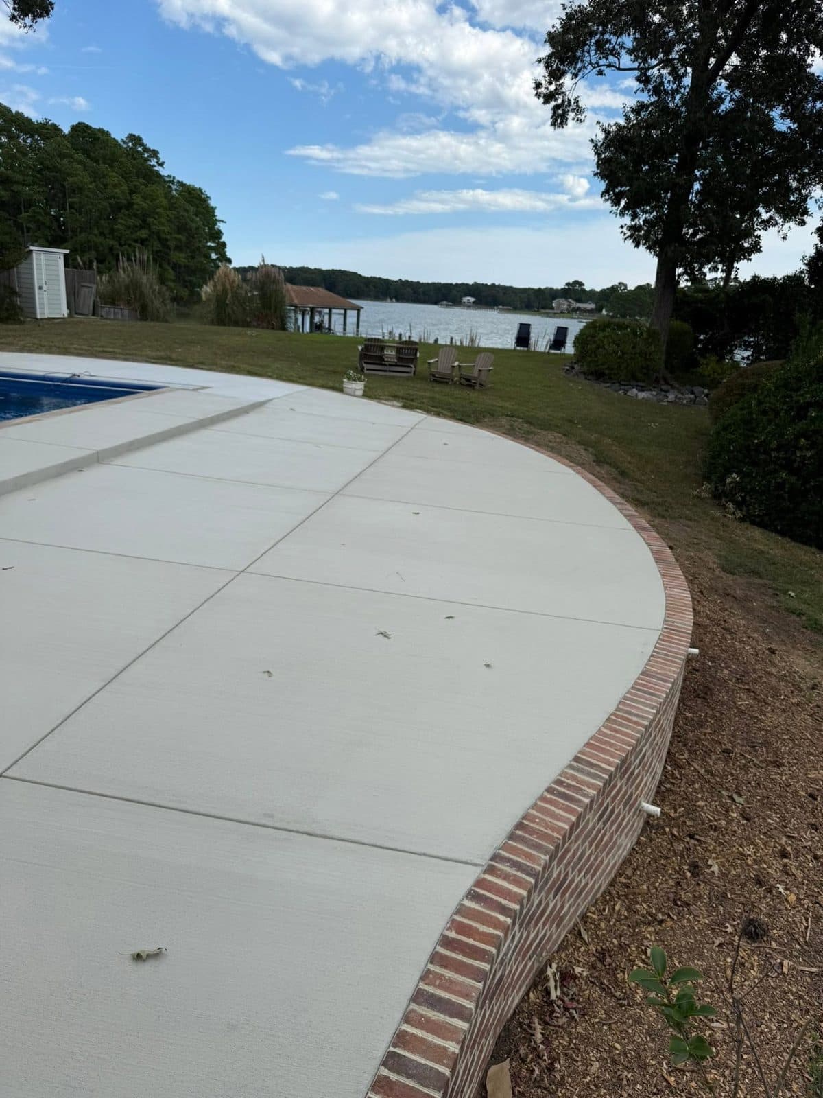 Concrete pool deck with brick edge beside a lake in Virginia Beach
